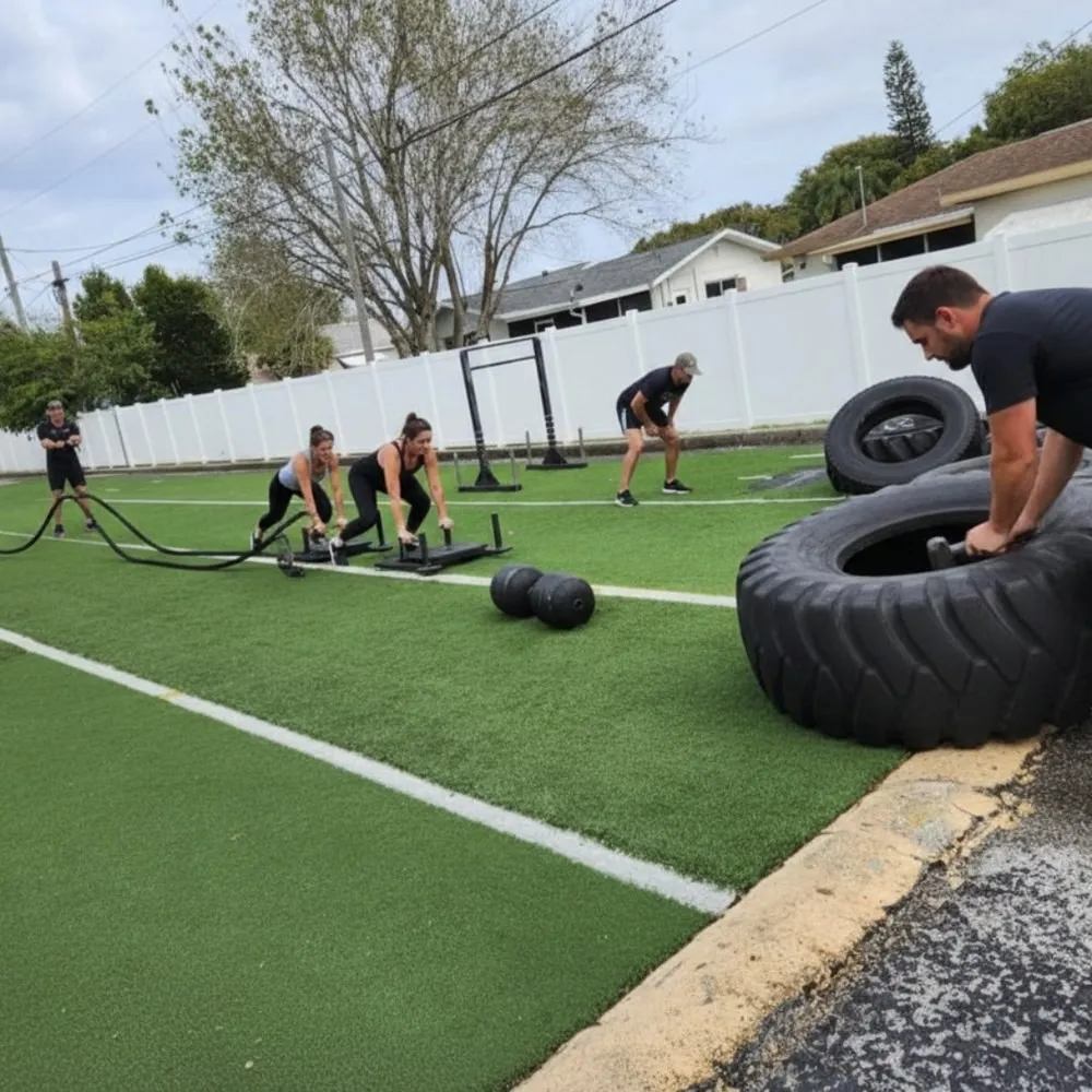 Members training with sleds and tires on the outdoor turf at Momentum